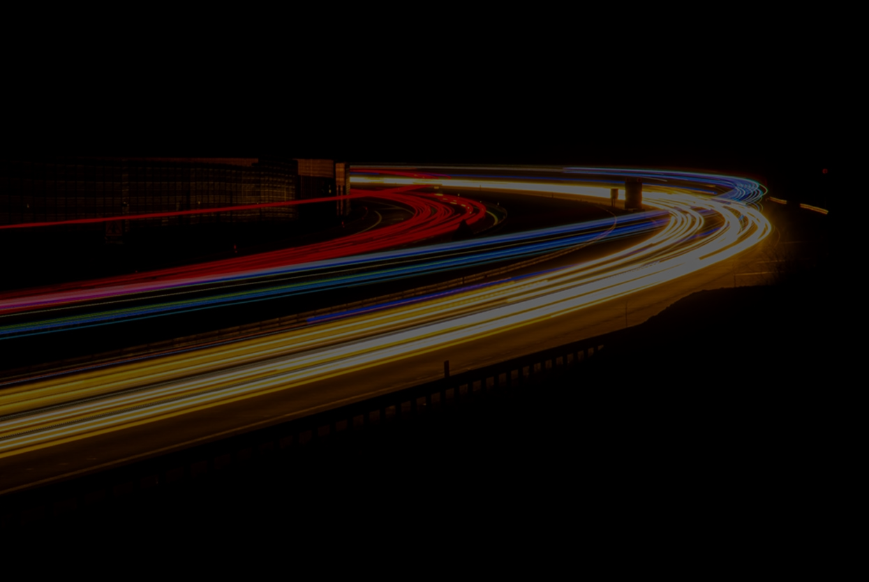 Lichtspuren von Fahrzeugen auf einer Autobahn bei Nacht, die Bewegung und Geschwindigkeit im Straßenverkehr darstellen.