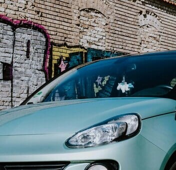 Un'auto blu è parcheggiata davanti a un muro cittadino coperto di graffiti.