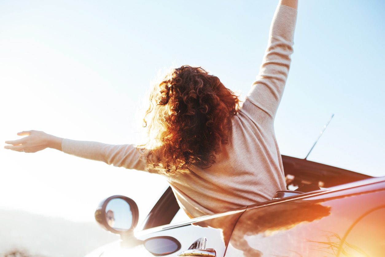 Eine Frau feiert voller Freude aus dem Fenster ihres Autos