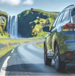 Foto van een waterstofauto op zonne-energie op een landweggetje. Aan het einde van de weg is een waterval te zien.