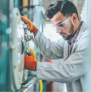 Een monteur in een witte jas en oranje handschoenen controleert de druk op een LPG-opslagtank.