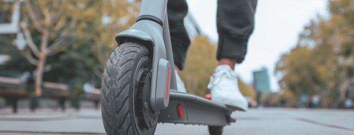Een man met witte sportschoenen staat op een elektrische scooter.
