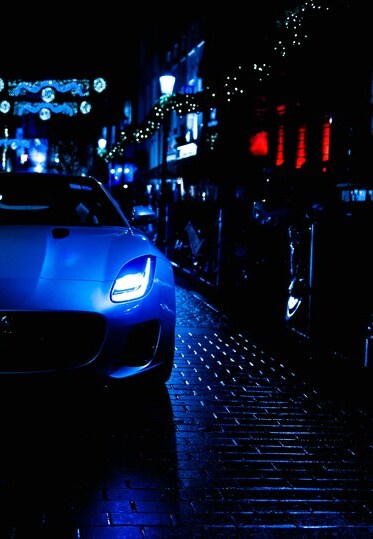 Je ziet de helft van een auto rijden op een donkere, natte straat in de stad.